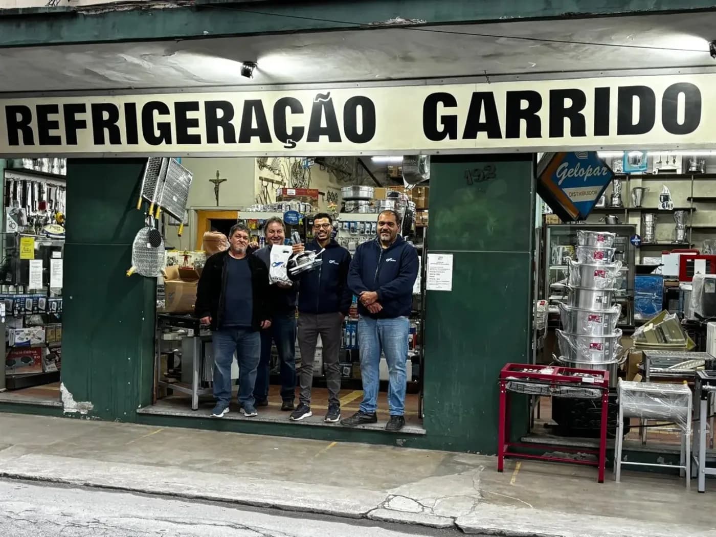 Equipe da Refrigeração Garrido na porta da loja, sob o letreiro